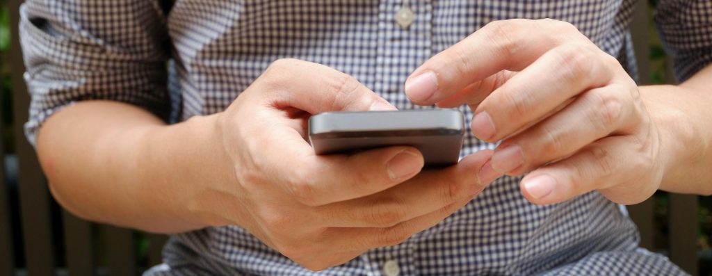 Contato. Imagem de um telemóvel em mãos.